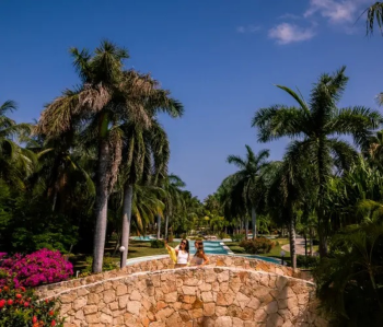 Guests walking across a stone bridge
surrounded by lush tropical landscaping at El Dorado Royale Riviera Maya in
Mexico.