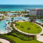 Aerial view of Dreams Playa Mujeres family resort with pools, palm-lined lawn, and Caribbean beach in the background