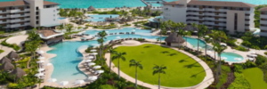 Aerial view of Dreams Playa Mujeres family resort with pools, palm-lined lawn, and Caribbean beach in the background